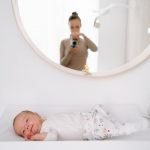 5 tips voor een ontspannen newborn fotosessie – NANI IS MOOI - Kleine baby op verschoonkussen in lichtte kamer, met spiegelbeeld van fotograaf in de spiegel.